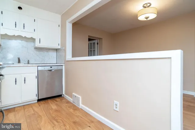 a view of a kitchen with white cabinets and wooden floor