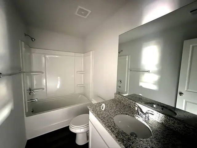a bathroom with a granite countertop sink toilet and shower