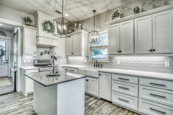 a kitchen with stainless steel appliances granite countertop a sink dishwasher a refrigerator and cabinets with wooden floor