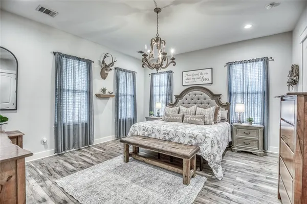 a bedroom with a bed chandelier and a window