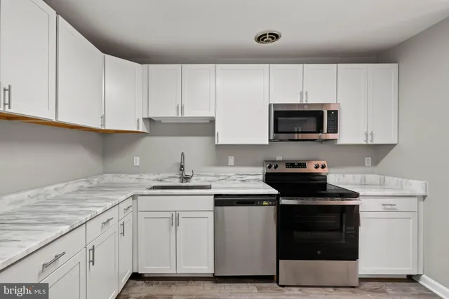 a kitchen with cabinets appliances a sink and a counter top