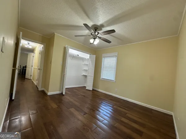 a view of empty room with wooden floor and fan