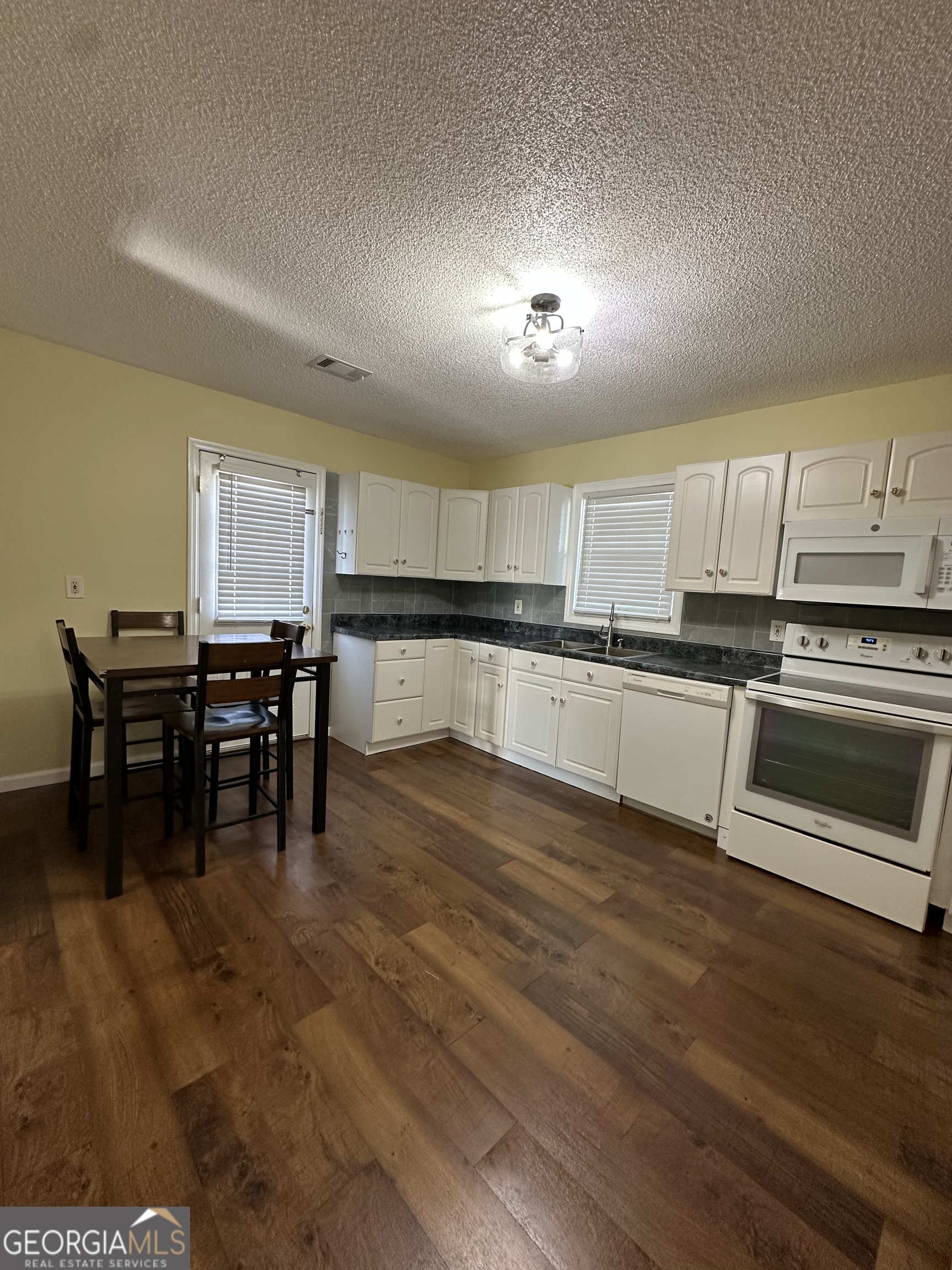 306 Garner Street Thomaston, GA 30286 - Photo 49 of 59 a kitchen with stainless steel appliances granite countertop a stove top oven a sink dishwasher a dining table and chairs with wooden floor
