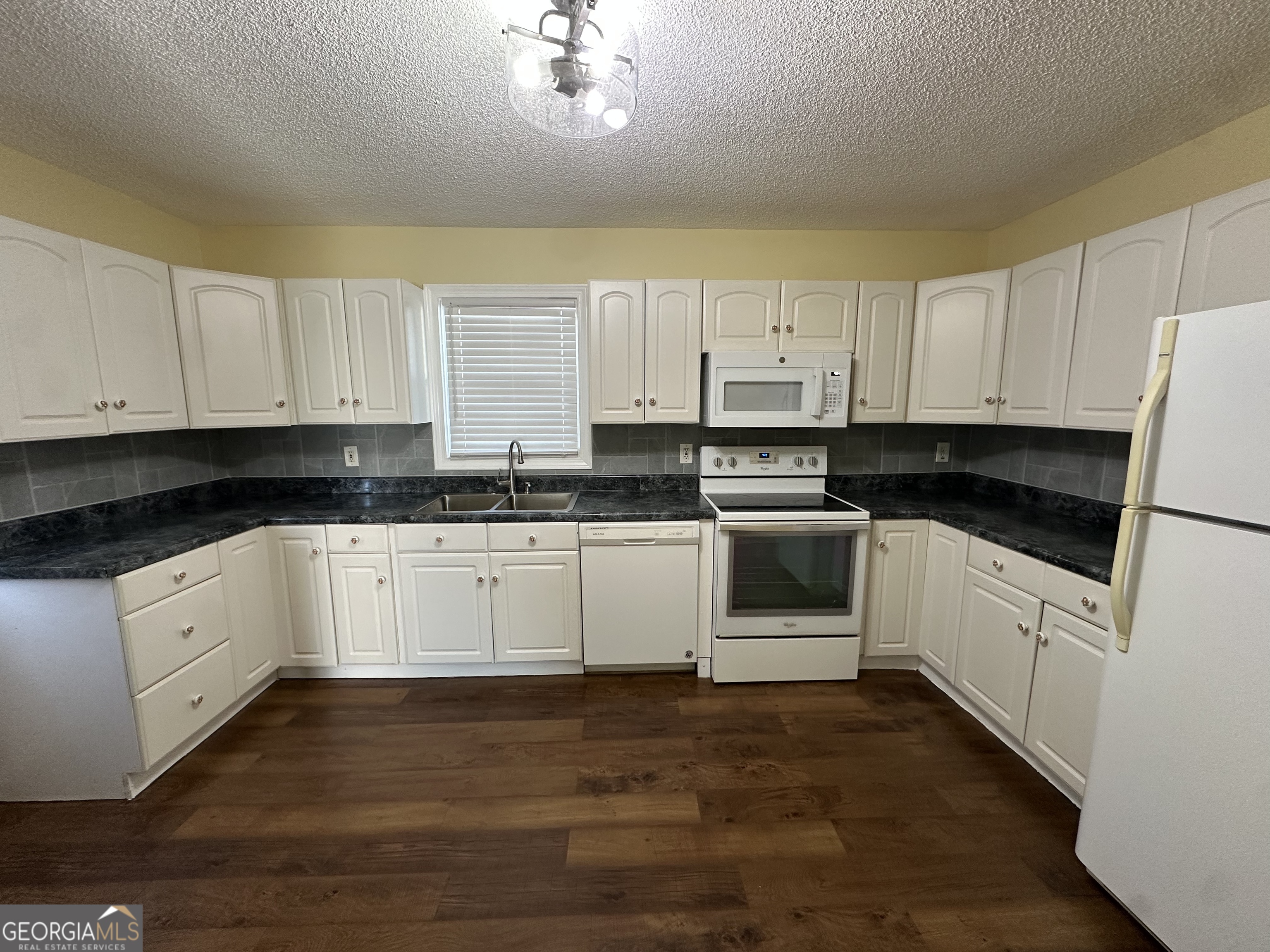 306 Garner Street Thomaston, GA 30286 - Photo 50 of 59 a kitchen with granite countertop white cabinets and white appliances