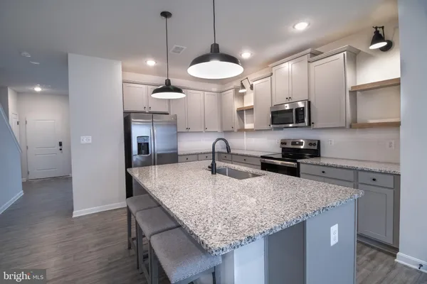 a kitchen with granite countertop kitchen island a sink and a wooden floor