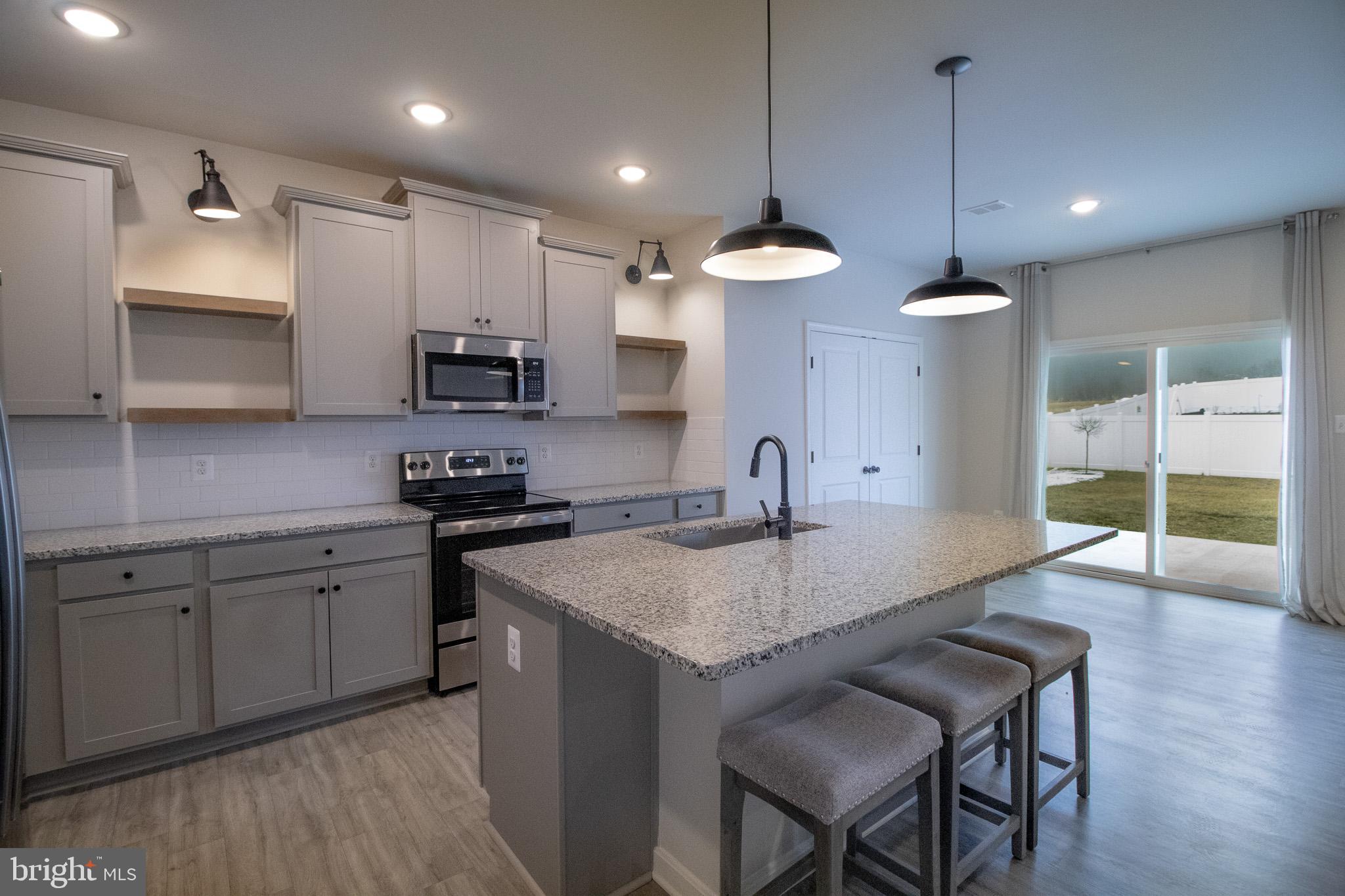 154 Diving Scaup Road Hedgesville, WV 25427 - Photo 21 of 57 a kitchen with stainless steel appliances granite countertop a sink a stove a microwave a center island and cabinets