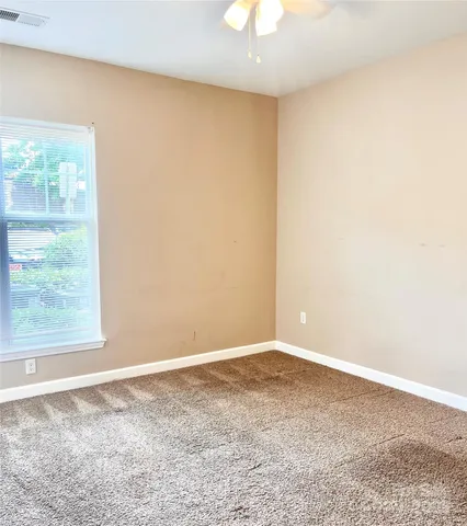 an empty room with windows and ceiling fan