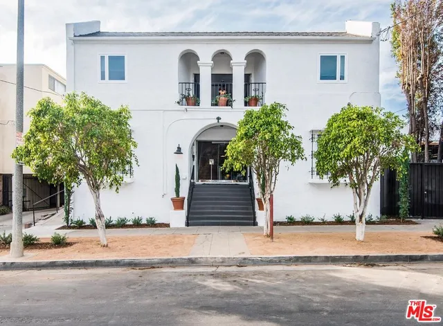 a view of a white house with a potted plants and a large tree