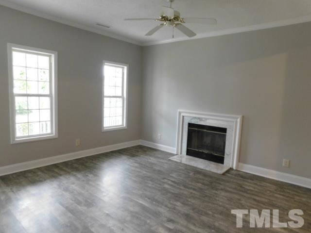 4121 Beaufain Street Raleigh, NC 27604 - Photo 5 of 18 an empty room with wooden floor a fireplace and windows