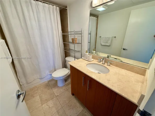 a bathroom with a granite countertop sink toilet and shower