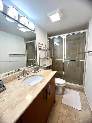 a bathroom with a sink a toilet a mirror and shower