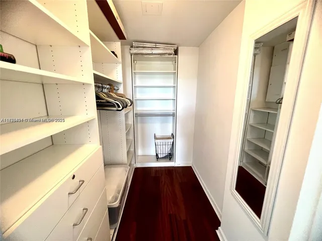 a walk in closet with wooden floor