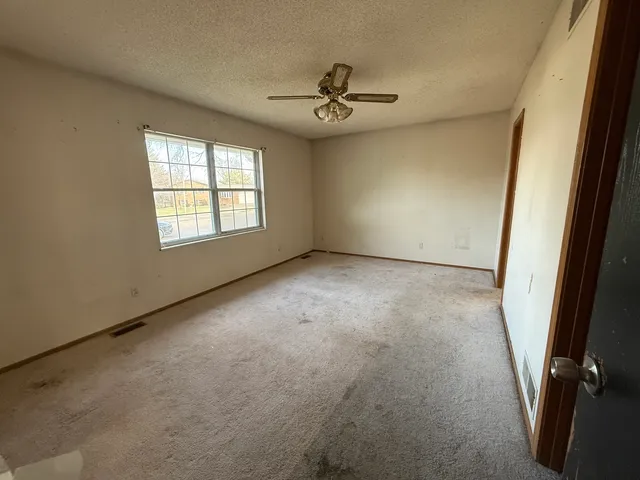 an empty room with windows and fan