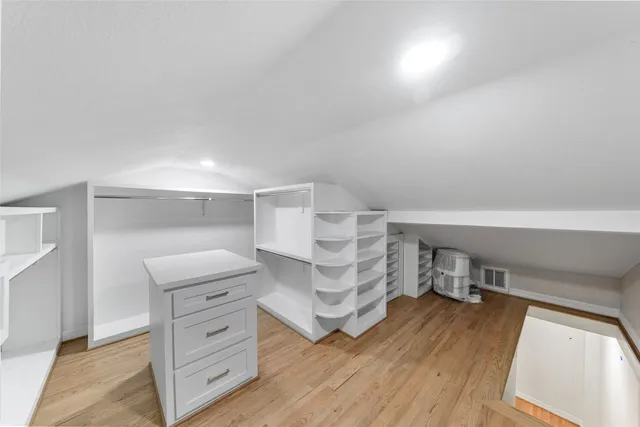 a view of walk in closet with furniture and wooden floor