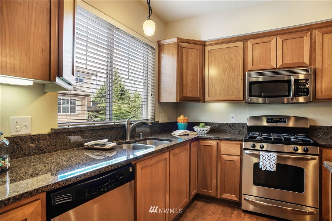 4651 Northeast 3rd Court, Unit A2 Renton, WA 98059 - Photo 14 of 24 a kitchen with stainless steel appliances granite countertop a sink a stove a microwave and cabinets