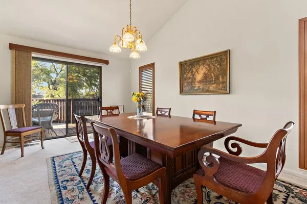 a view of a dining room with furniture a chandelier and large windows