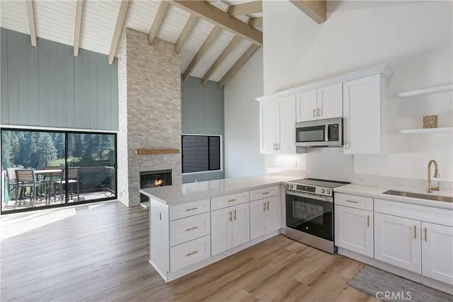 a kitchen with stainless steel appliances granite countertop a stove top oven a sink dishwasher a dining table and chairs with wooden floor