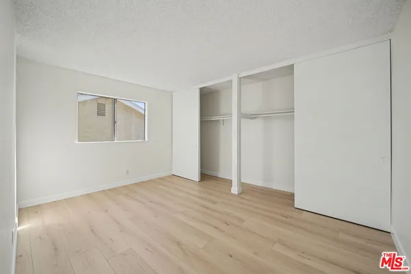 an empty room with wooden floor closet and windows