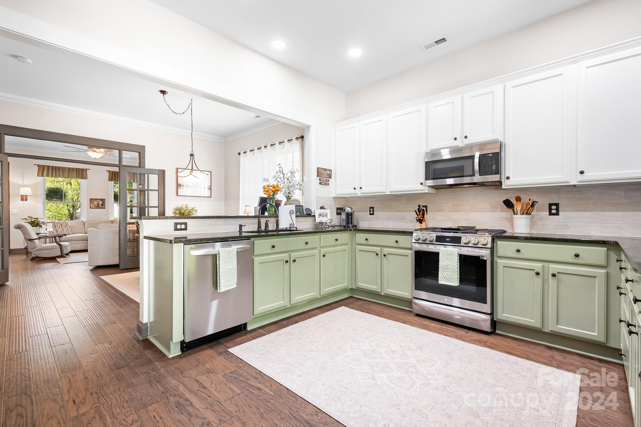 2607 Nations Commons Street Fort Mill, SC 29708 - Photo 12 of 40 a kitchen with stainless steel appliances white cabinets a sink a stove a refrigerator and island with wooden floor