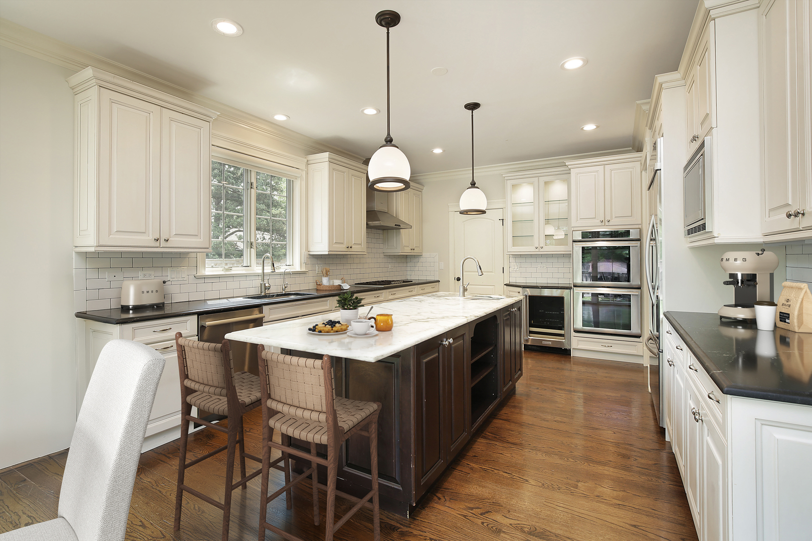 2215 Pinehurst Drive Glenview, IL 60025 - Photo 6 of 31 a kitchen with a stove a sink a kitchen island with chairs and cabinets