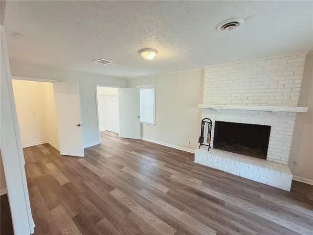 a view of empty room with wooden floor and fireplace