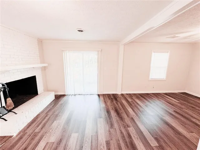 a view of empty room with wooden floor and window