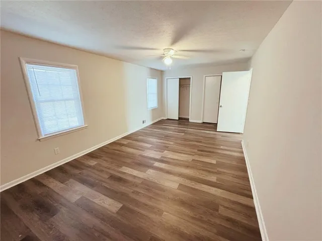 an empty room with wooden floor and windows