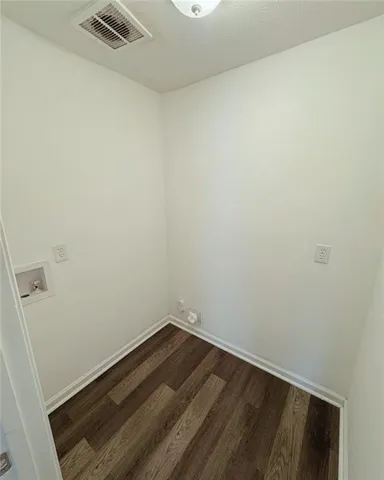 a view of an empty room with wooden floor and a ceiling fan