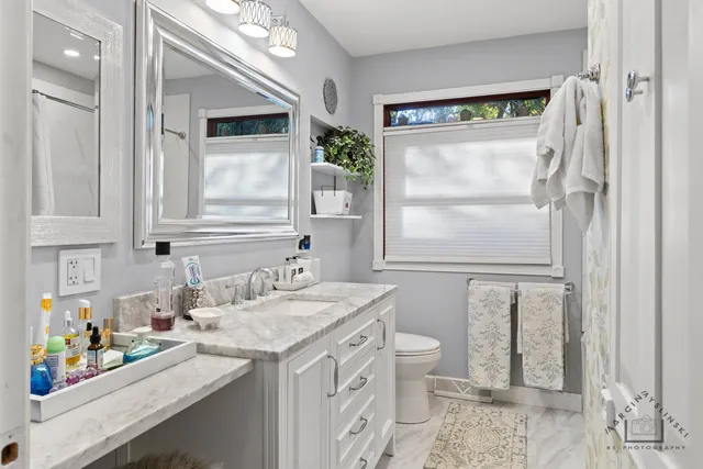 a bathroom with a granite countertop sink a toilet a large mirror and shower