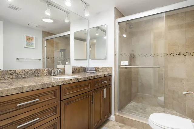 a bathroom with a granite countertop sink toilet and shower