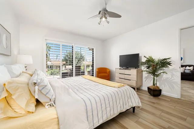 a bedroom with a bed a large window and flat screen tv
