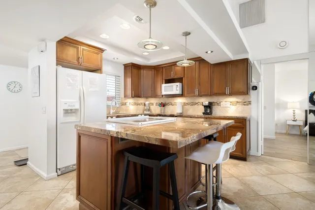 a kitchen with stainless steel appliances granite countertop a sink a stove a refrigerator and a refrigerator
