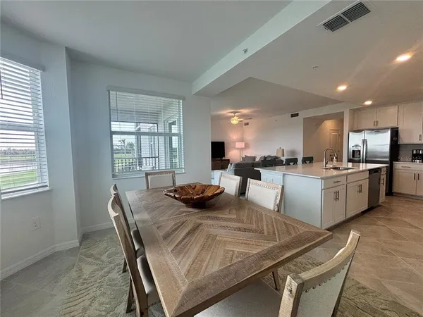 a kitchen with a table chairs a window and white cabinets