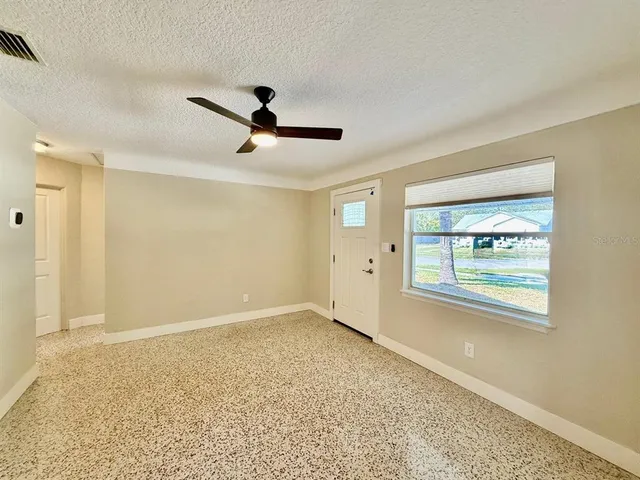 a view of an empty room with window and wooden floor