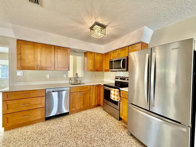 a kitchen with granite countertop stainless steel appliances a refrigerator stove microwave and cabinets
