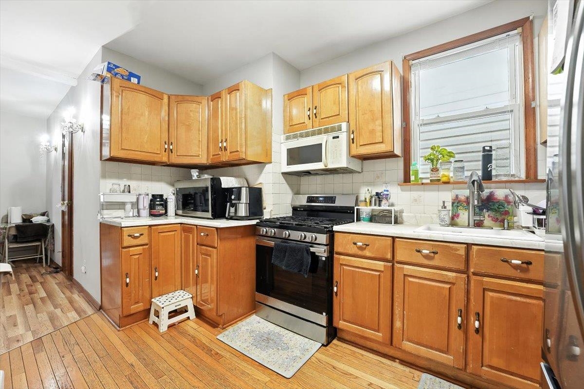 175 Van Winkle Avenue, Unit 1 Jersey City, NJ 07306 - Photo 4 of 14 a kitchen with stainless steel appliances granite countertop a stove a sink dishwasher and a refrigerator with wooden floor
