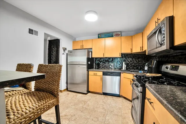 a kitchen with stainless steel appliances granite countertop a refrigerator and a stove top oven
