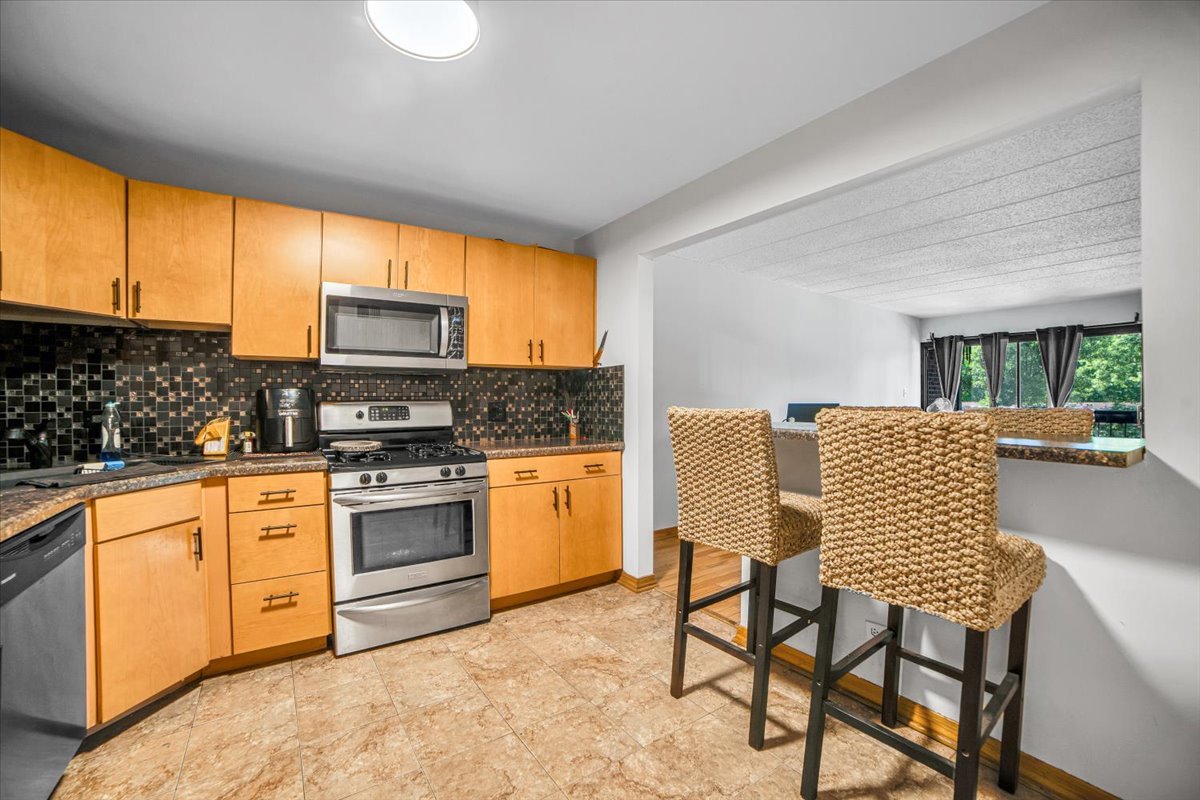 14511 Central Court, Unit M2 Oak Forest, IL 60452 - Photo 9 of 38 a kitchen with stainless steel appliances granite countertop a stove top oven a sink with a dining table and chairs