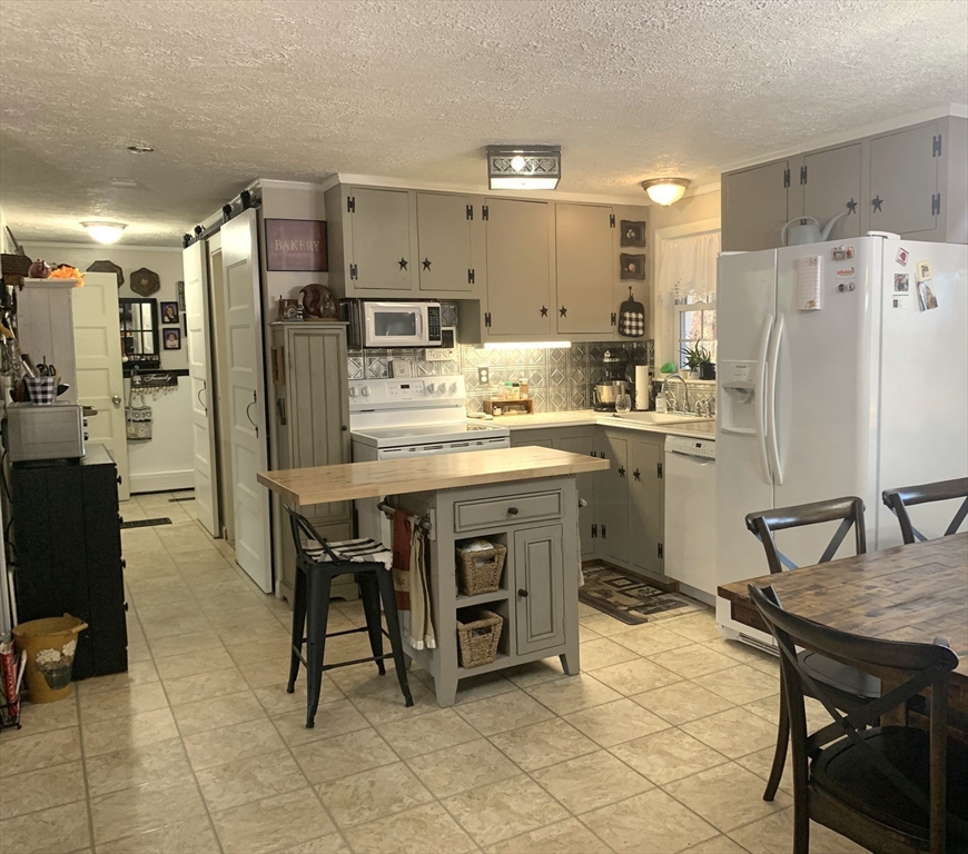 21 Sullivan Road Charlton, MA 01507 - Photo 6 of 35 a kitchen with refrigerator and chairs