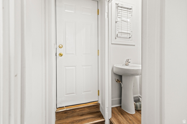 69 South Main Street Manti, UT 84642 - Photo 16 of 44 White paneled door with brass hardware, wood-finish flooring, and a white pedestal sink with a window featuring blinds