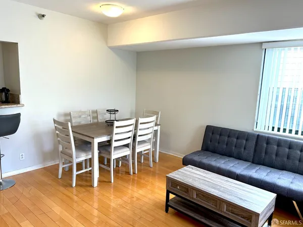 a living room with furniture and a dining table with wooden floor