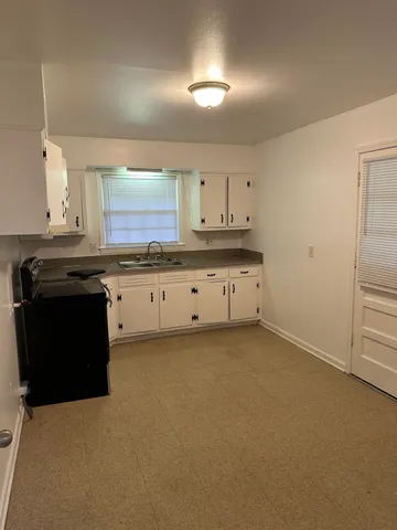 a kitchen with granite countertop a sink a stove and cabinets