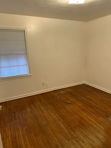 a view of an empty room with wooden floor and cabinet