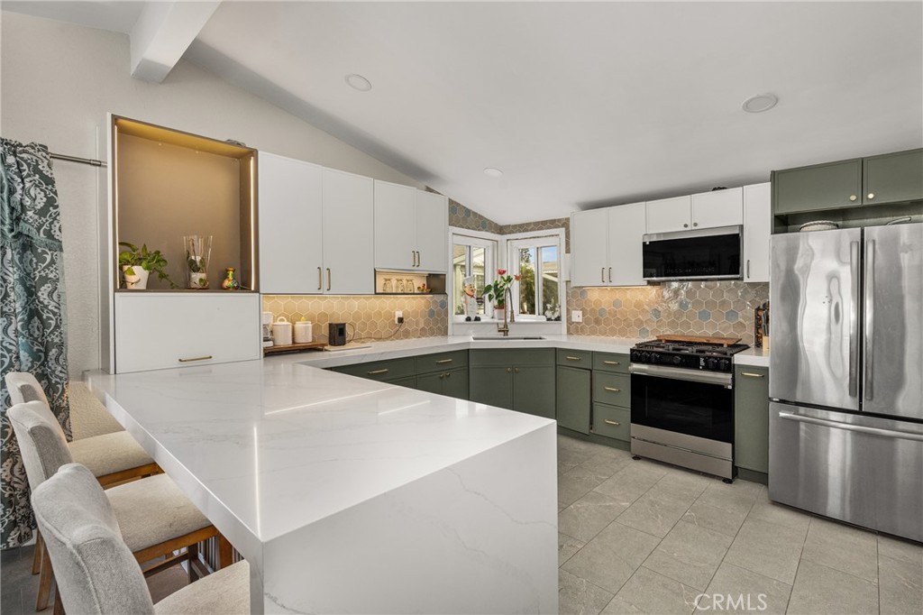 23301 Ridge Rte Drive, Unit 56 Laguna Hills, CA 92653 - Photo 13 of 44 a kitchen with stainless steel appliances kitchen island granite countertop a refrigerator stove top oven and sink