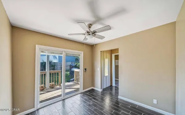 an empty room with wooden floor and a ceiling fan