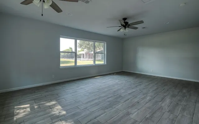 an empty room with windows and fan