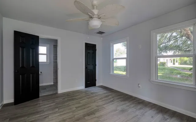 wooden floor in an empty room with a chandelier fan