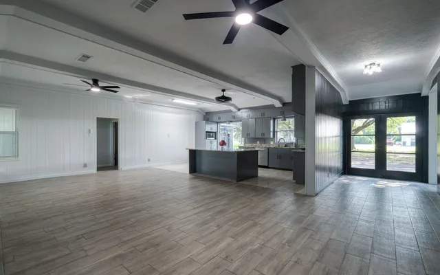 a view of an empty room with a window and wooden floor
