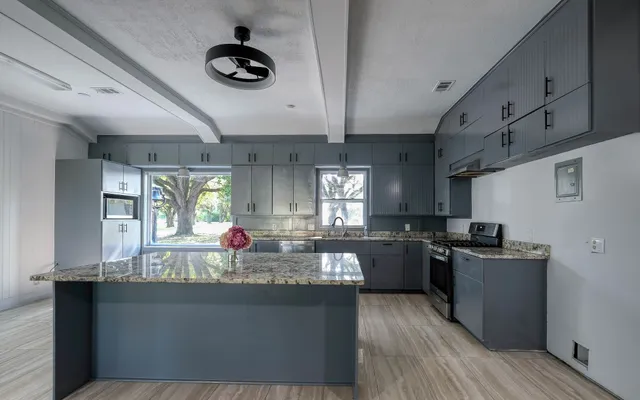 a kitchen with stainless steel appliances granite countertop a sink dishwasher stove and wooden cabinets