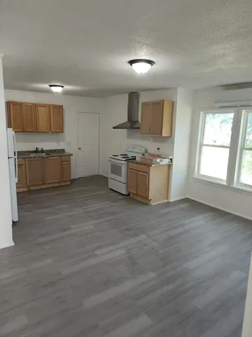 a large kitchen with stainless steel appliances granite countertop a stove and a wooden floors